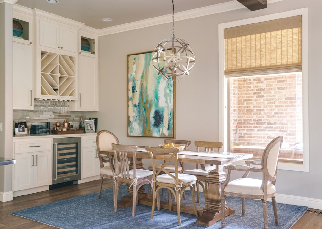 A cozy dining room with a blue rug, sleek white cabinets and earth-tone high-end roman shades