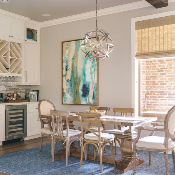 A cozy dining room with a blue rug, sleek white cabinets and earth-tone high-end roman shades