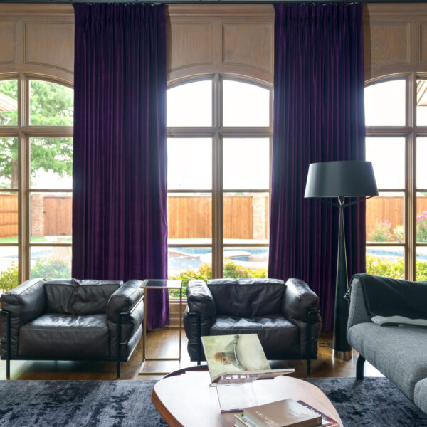 A stylish living room with luxury purple velvet curtains and sleek black leather furniture.